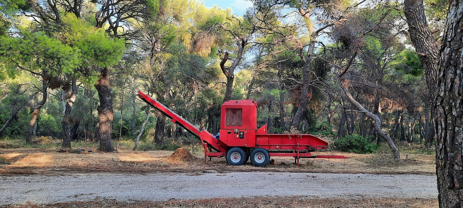 Astilladora remolcable en un claro del bosque, junto a restos de poda